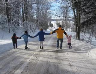 Family holding hands across a snowy road