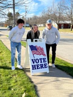 students with vote here sign